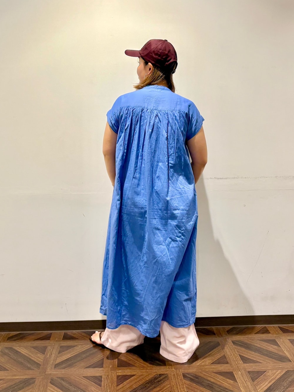 ブルー系のワンピース、ブラウン系のサンダル、ブラウン系のキャップを着用したレディースの夏コーディネートの2枚目の写真