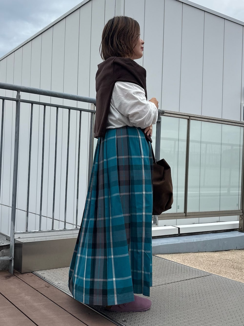 グリーン系のスカート、ブラウン系のカーディガン/ボレロ、ホワイト系のTシャツ/カットソーを着用したレディースの秋コーディネートの2枚目の写真