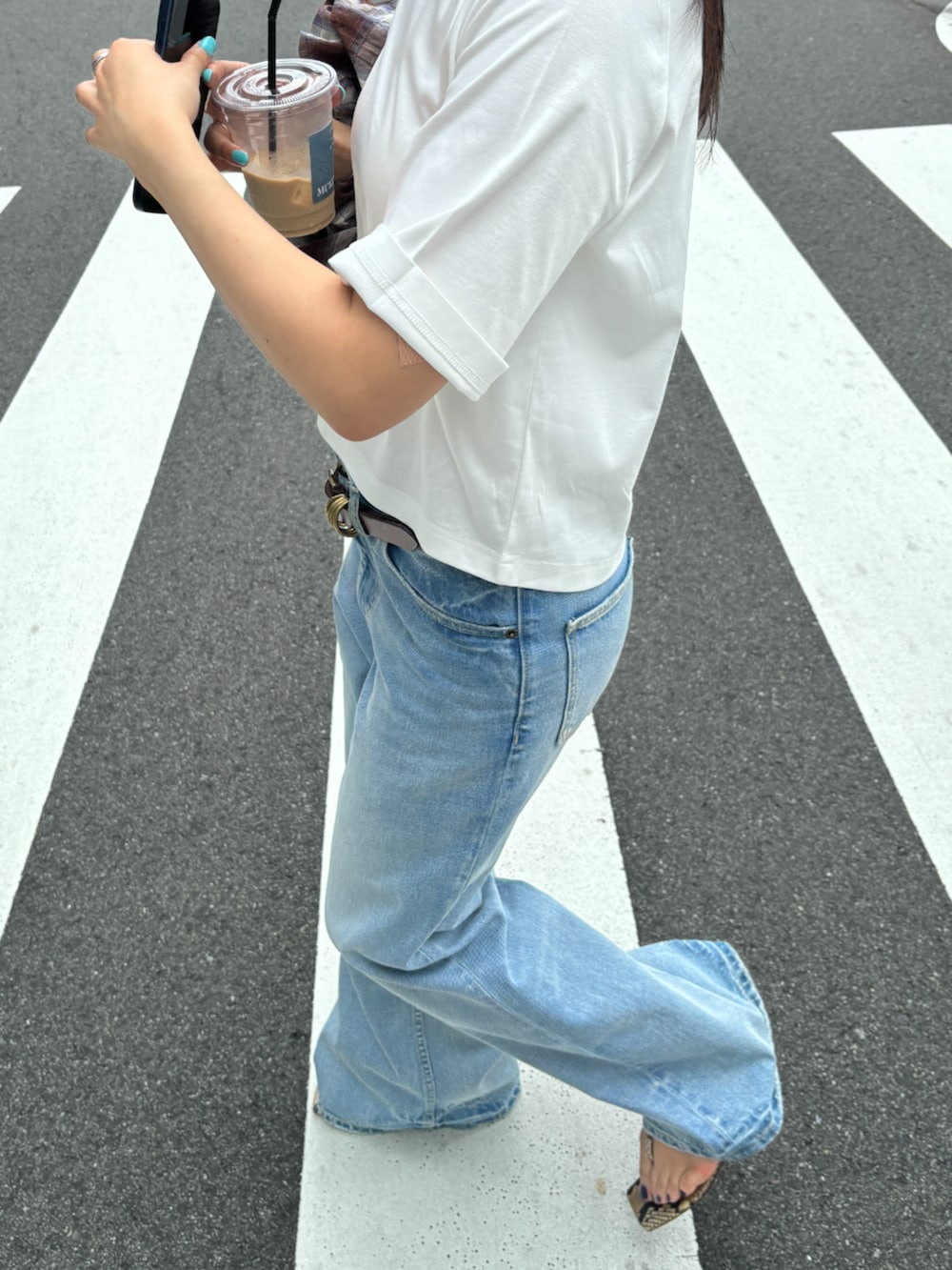 ブルー系のデニムパンツ、ブラウン系のベルトを着用したレディースの春コーディネートの2枚目の写真