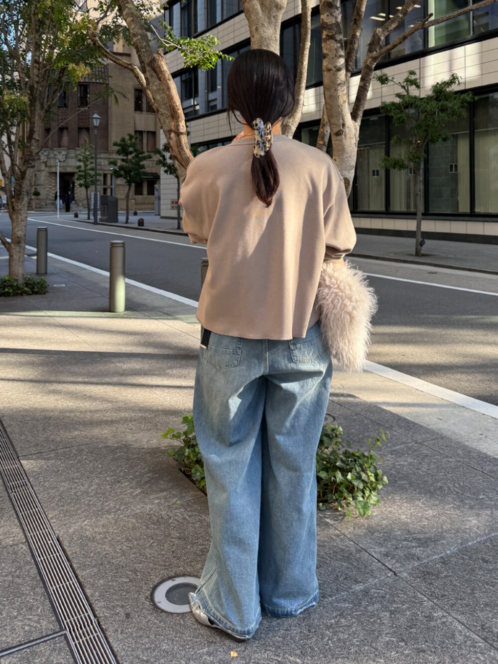 ブルー系のデニムパンツ、ベージュ系のTシャツ/カットソー、ホワイト系のショルダーバッグを着用したレディースの冬コーディネートの3枚目の写真