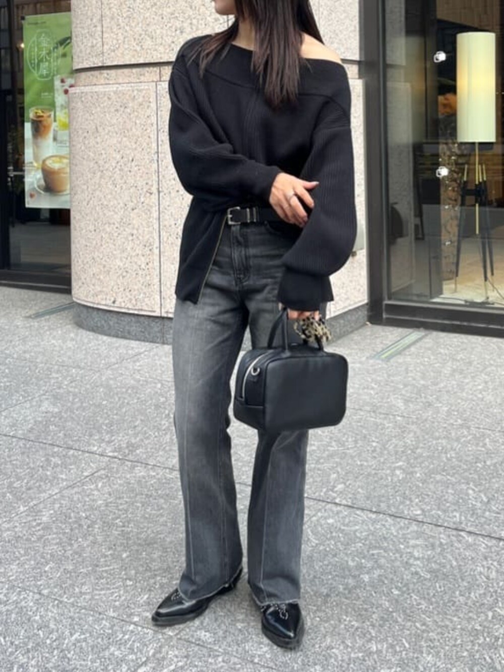 ブラック系のデニムパンツ、ブラック系のニット/セーター、ブラック系のショルダーバッグを着用したレディースの秋コーディネートの2枚目の写真