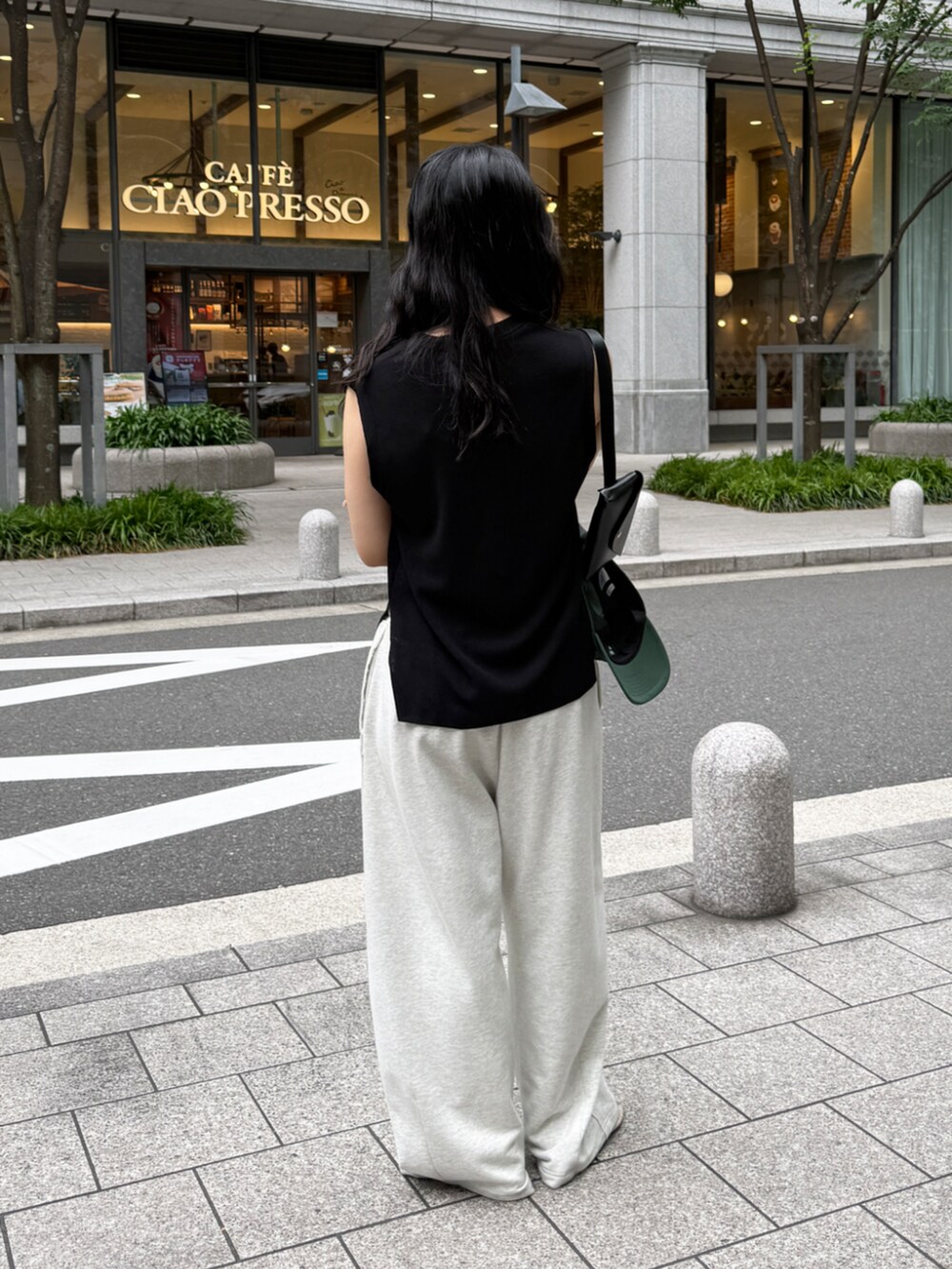 ブラック系のニット/セーター、ブラック系のショルダーバッグ、ベージュ系のその他パンツを着用したレディースの春コーディネートの4枚目の写真