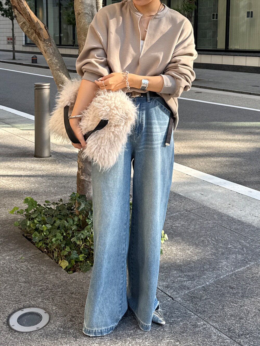 ブルー系のデニムパンツ、ベージュ系のTシャツ/カットソー、ホワイト系のショルダーバッグを着用したレディースの冬コーディネートの2枚目の写真