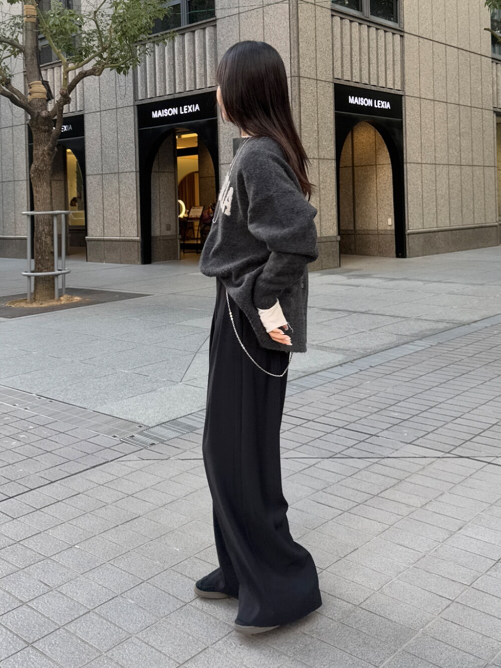 ブラック系のスラックス、グレー系のニット/セーター、ホワイト系のTシャツ/カットソーを着用したレディースの冬コーディネートの2枚目の写真