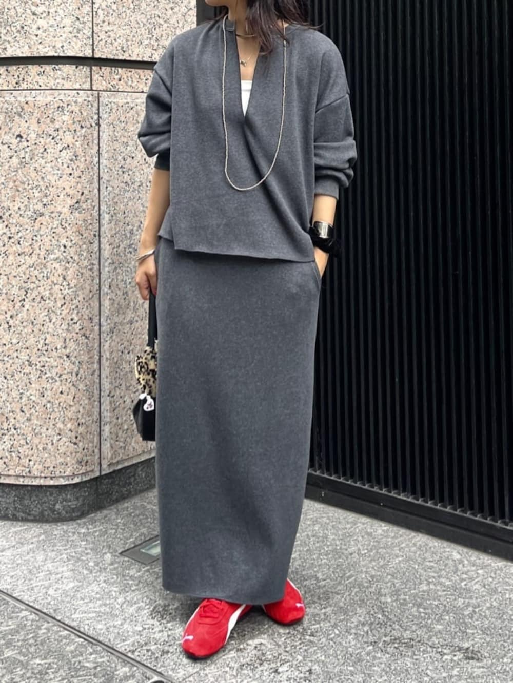 グレー系のスカート、グレー系のTシャツ/カットソー、レッド系のスニーカーを着用したレディースの秋コーディネートの4枚目の写真