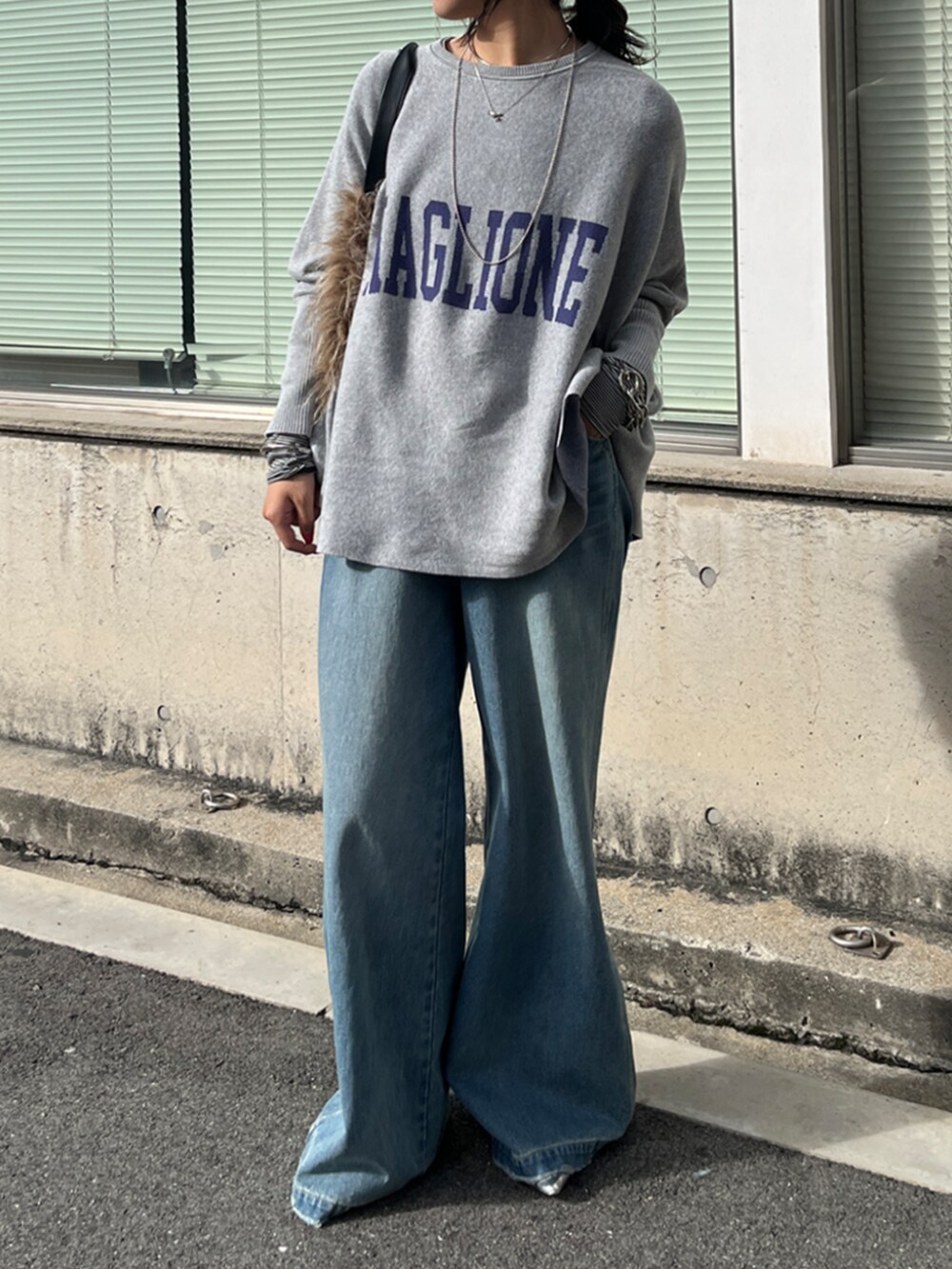 ブルー系のデニムパンツ、ホワイト系のTシャツ/カットソー、グレー系のニット/セーターを着用したレディースの秋コーディネートの3枚目の写真