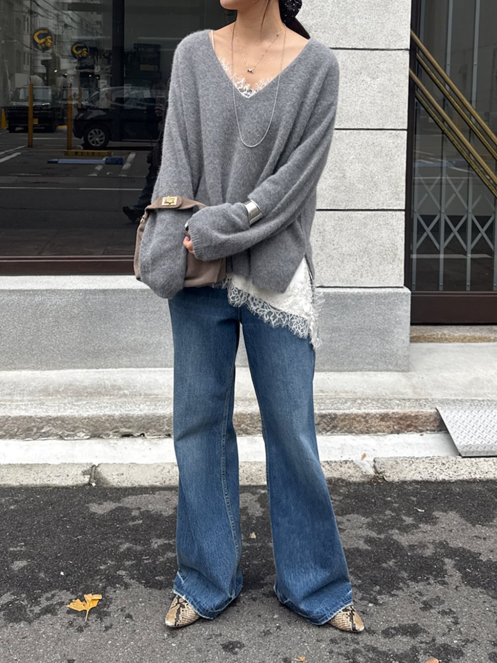 ブルー系のデニムパンツ、グレー系のニット/セーター、ホワイト系のシャツ/ブラウスを着用したレディースの冬コーディネートの2枚目の写真