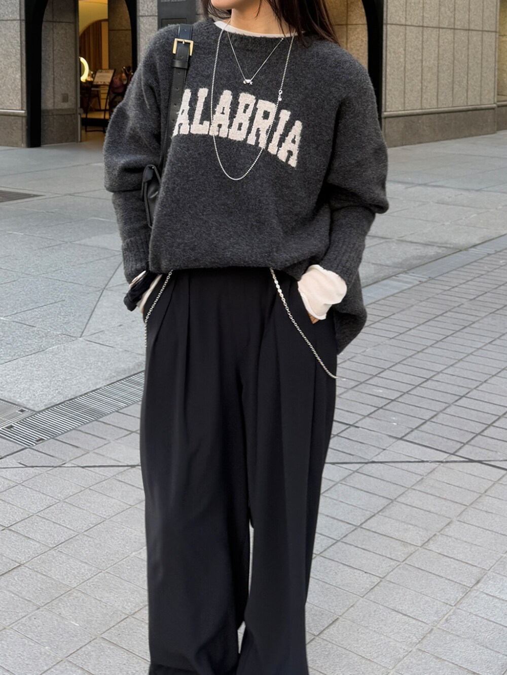 ブラック系のスラックス、グレー系のニット/セーター、ホワイト系のTシャツ/カットソーを着用したレディースの冬コーディネートの4枚目の写真