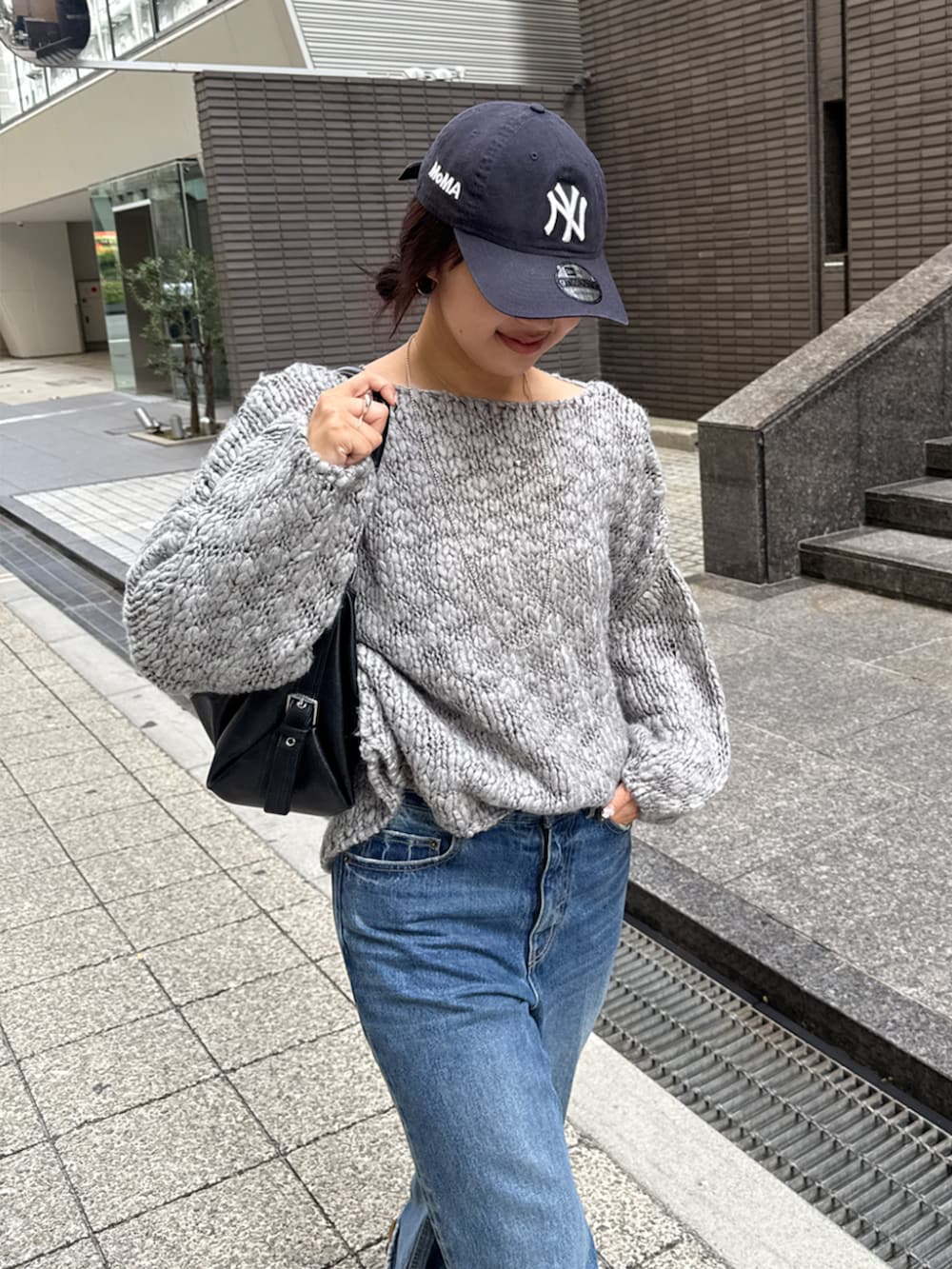 グレー系のニット/セーター、ブルー系のデニムパンツを着用したレディースの秋コーディネートの2枚目の写真