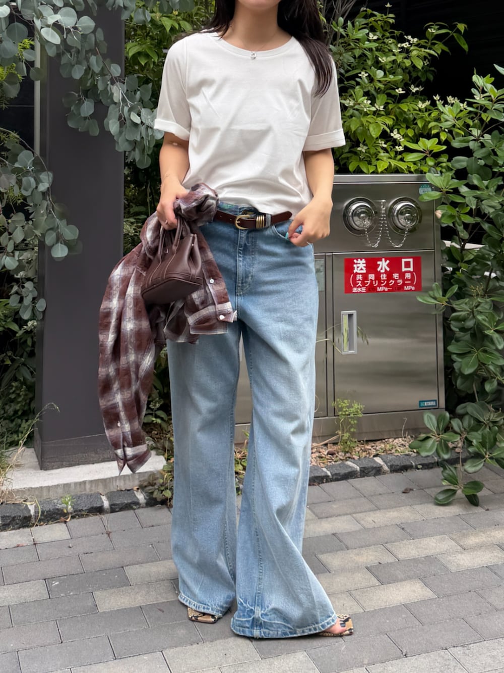 ブルー系のデニムパンツ、ブラウン系のベルトを着用したレディースの春コーディネートの3枚目の写真