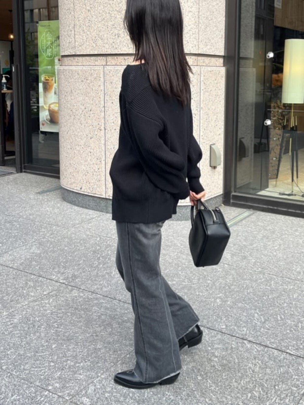 ブラック系のデニムパンツ、ブラック系のニット/セーター、ブラック系のショルダーバッグを着用したレディースの秋コーディネートの3枚目の写真