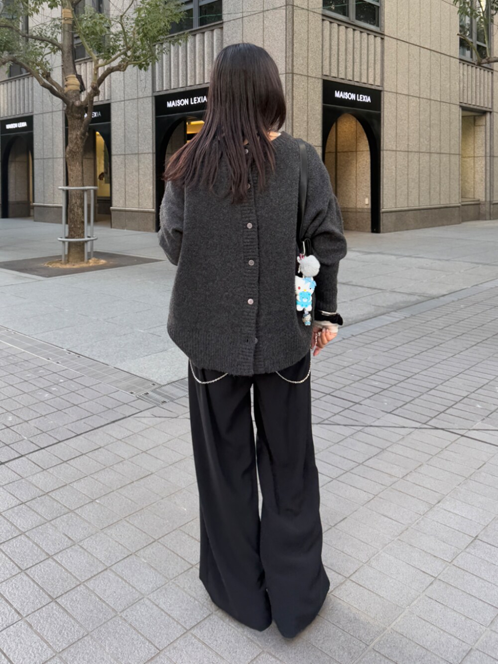 ブラック系のスラックス、グレー系のニット/セーター、ホワイト系のTシャツ/カットソーを着用したレディースの冬コーディネートの3枚目の写真