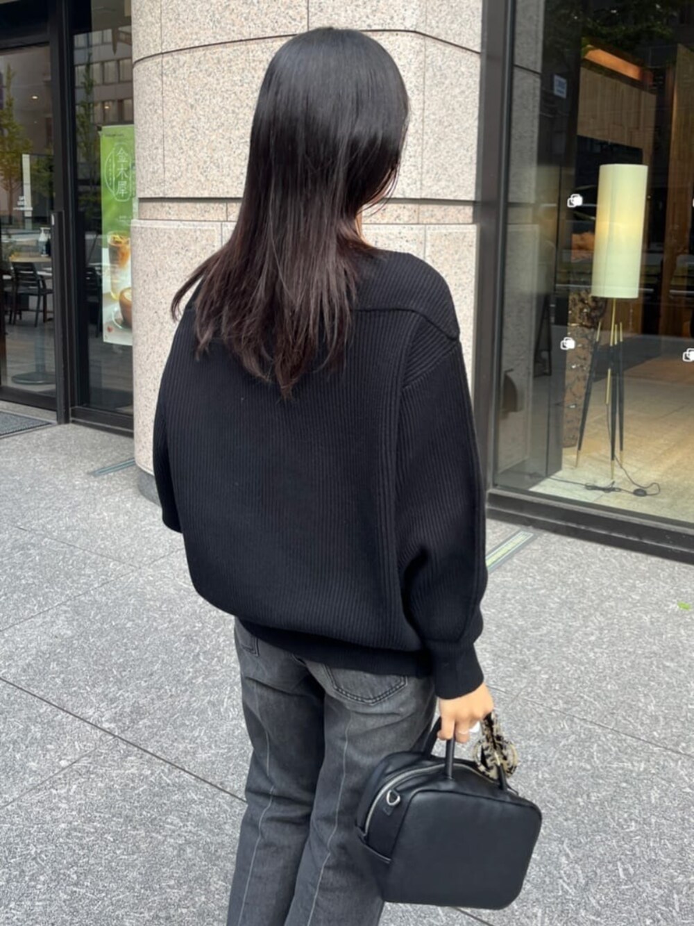 ブラック系のデニムパンツ、ブラック系のニット/セーター、ブラック系のショルダーバッグを着用したレディースの秋コーディネートの6枚目の写真