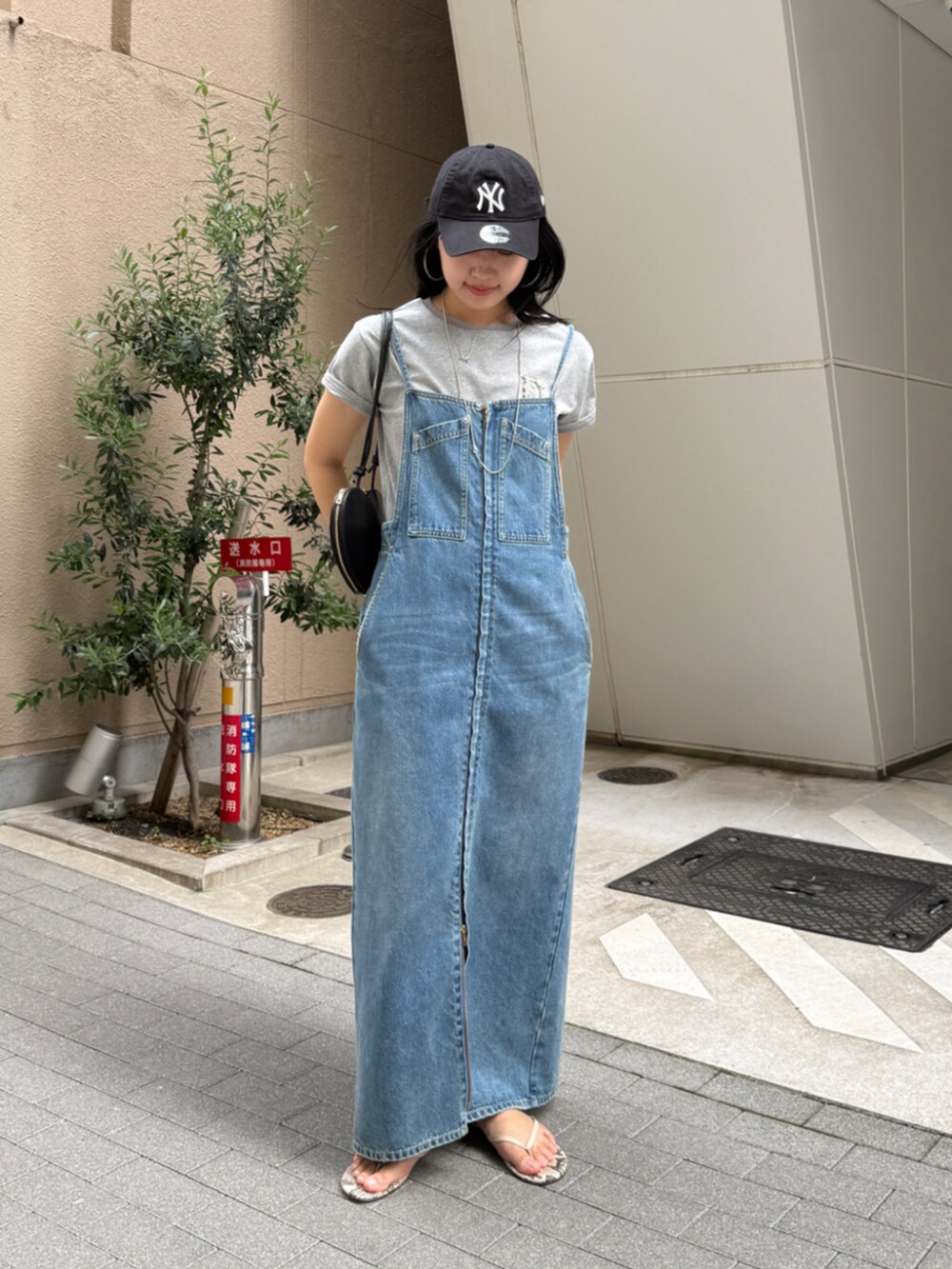 ブラック系のショルダーバッグ、ブルー系のワンピース、グレー系のTシャツ/カットソーを着用したレディースの春コーディネートの2枚目の写真