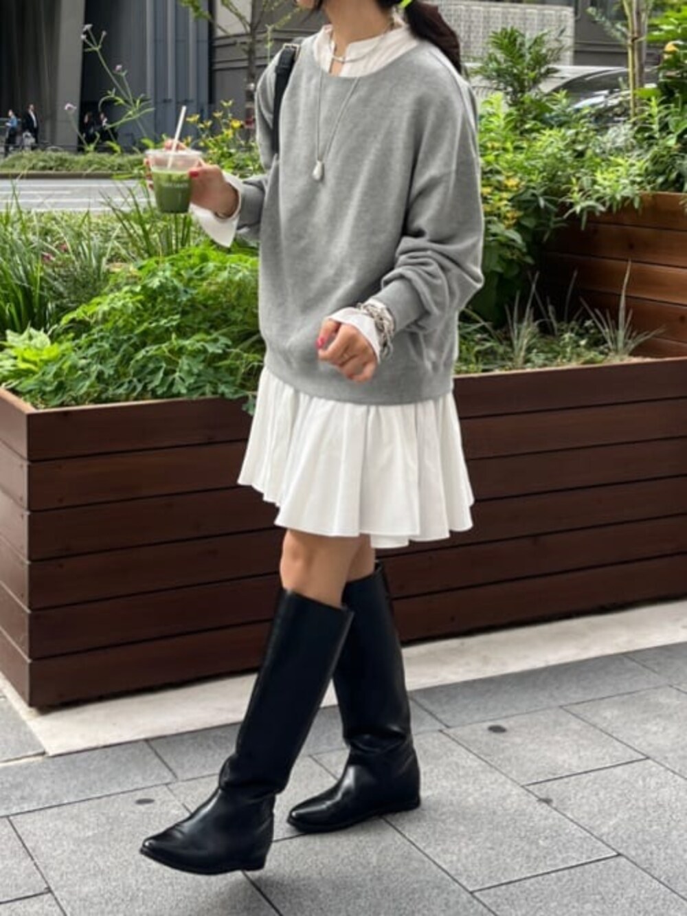 グレー系のスウェット、ホワイト系のシャツ/ブラウス、ブラック系のブーツを着用したレディースの秋コーディネートの2枚目の写真