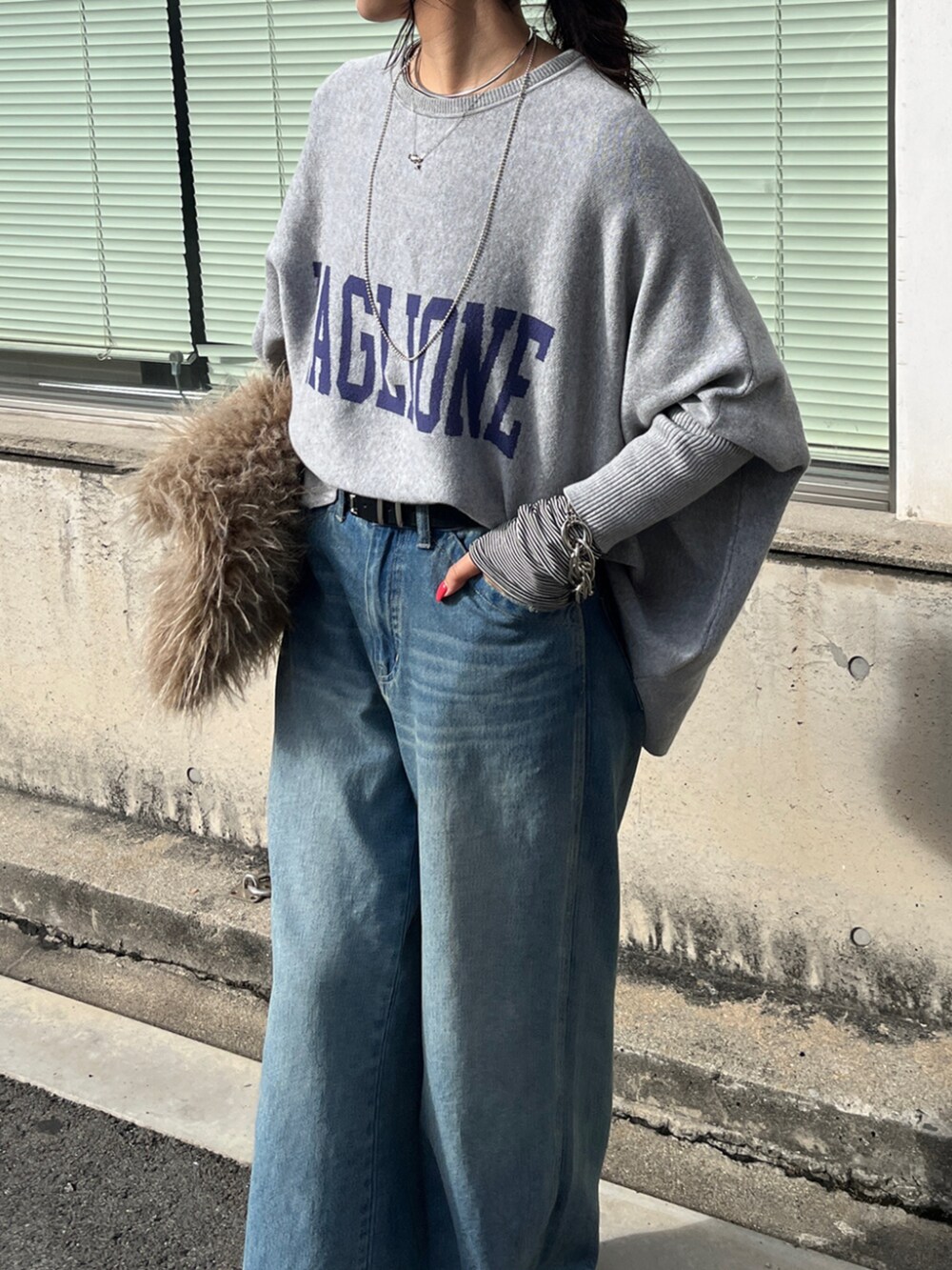 ブルー系のデニムパンツ、ホワイト系のTシャツ/カットソー、グレー系のニット/セーターを着用したレディースの秋コーディネートの2枚目の写真