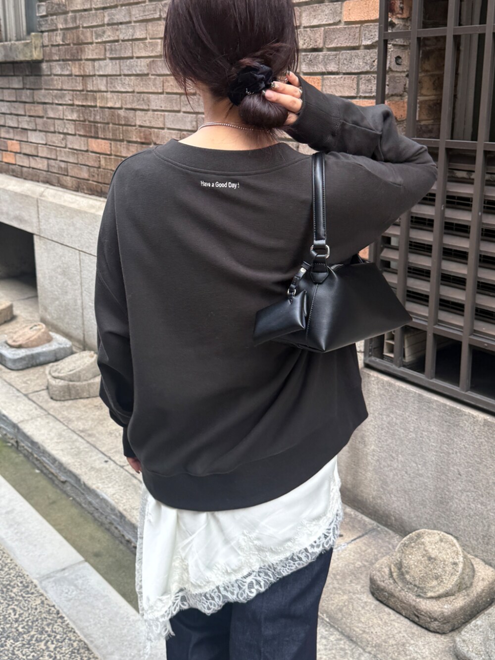 グレー系のスウェット、ホワイト系のキャミソール、ブルー系のデニムパンツを着用したレディースの秋コーディネートの3枚目の写真