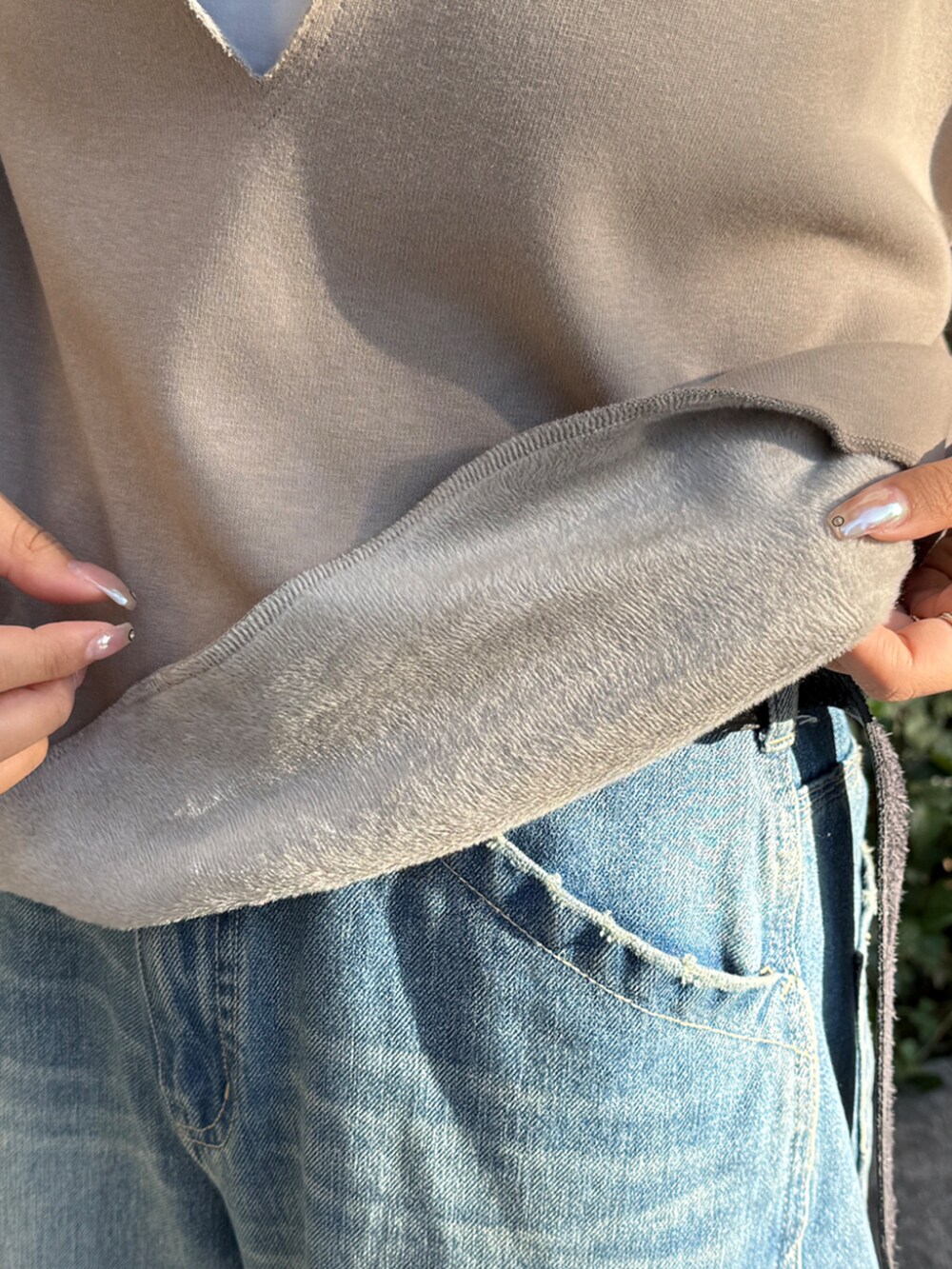 ブルー系のデニムパンツ、ベージュ系のTシャツ/カットソー、ホワイト系のショルダーバッグを着用したレディースの冬コーディネートの4枚目の写真