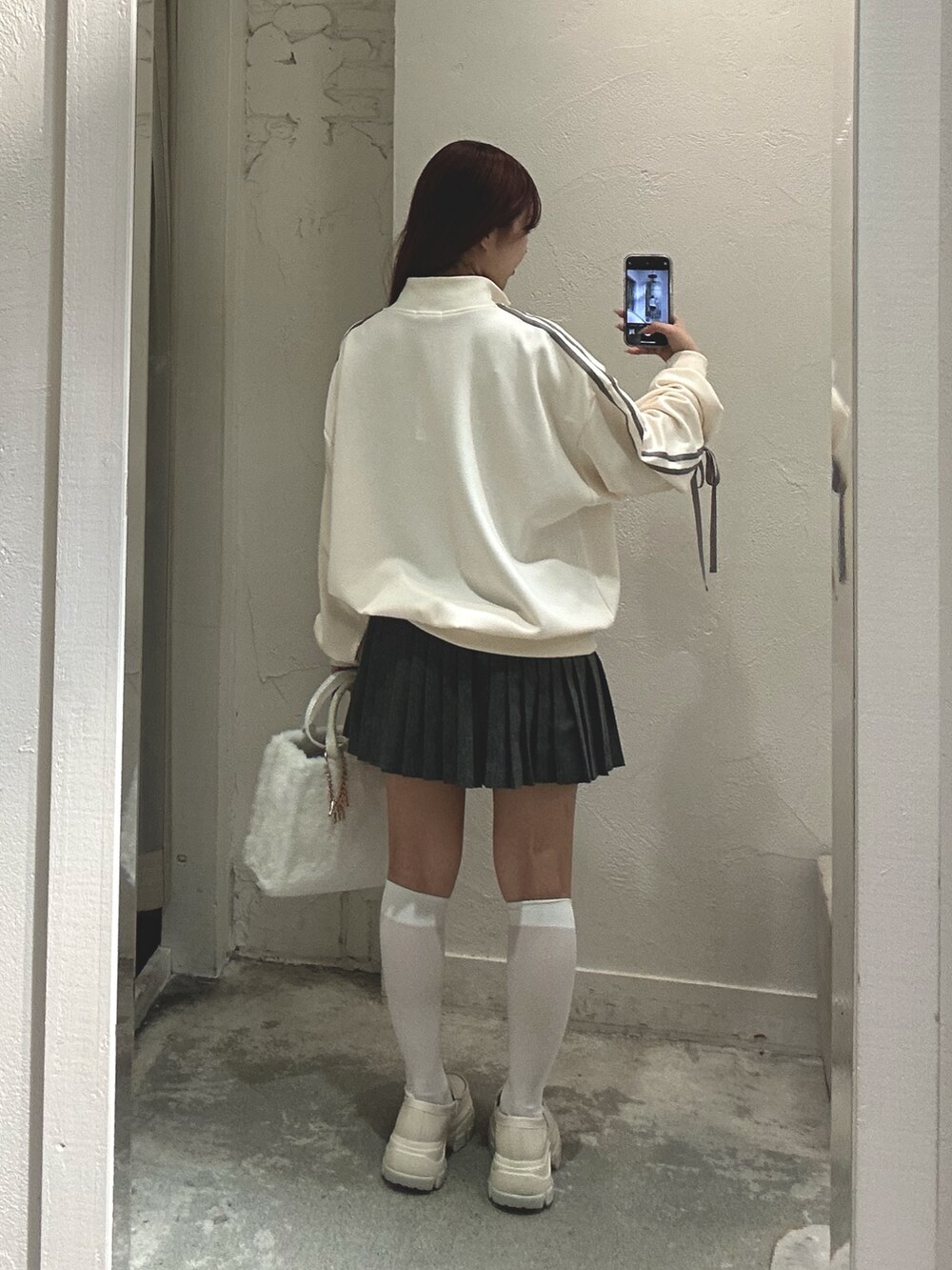 ホワイト系のジャージ、ホワイト系のトートバッグ、ホワイト系のローファーを着用したレディースの秋コーディネートの3枚目の写真