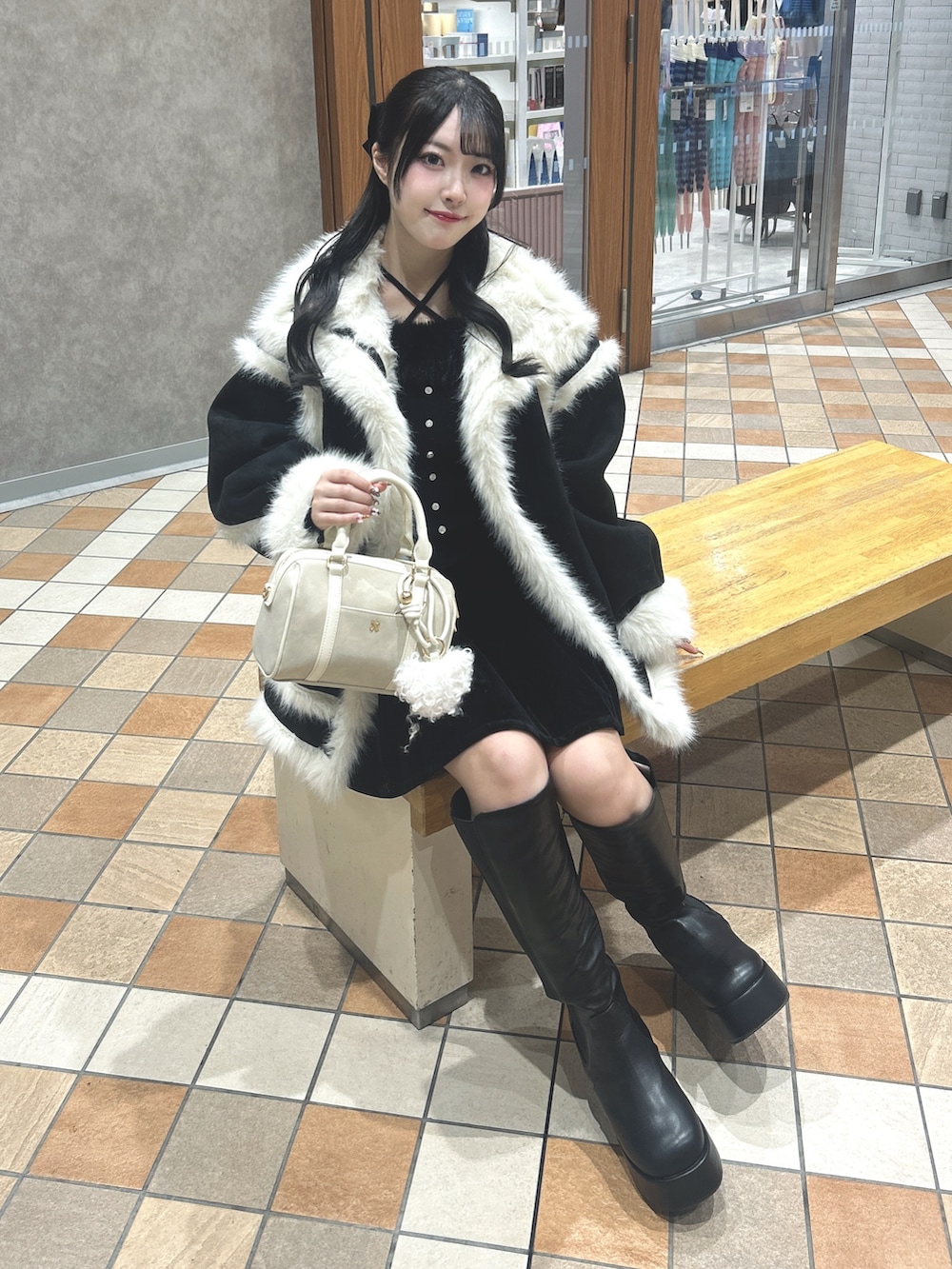 ブラック系のムートンコート、ブラック系のニット/セーター、ブラック系のスカートを着用したレディースの冬コーディネートの6枚目の写真