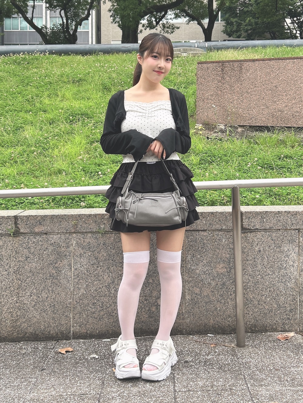 ブラック系のカーディガン/ボレロ、ブラック系のスカート、ホワイト系のサンダルを着用したレディースの夏コーディネートの4枚目の写真