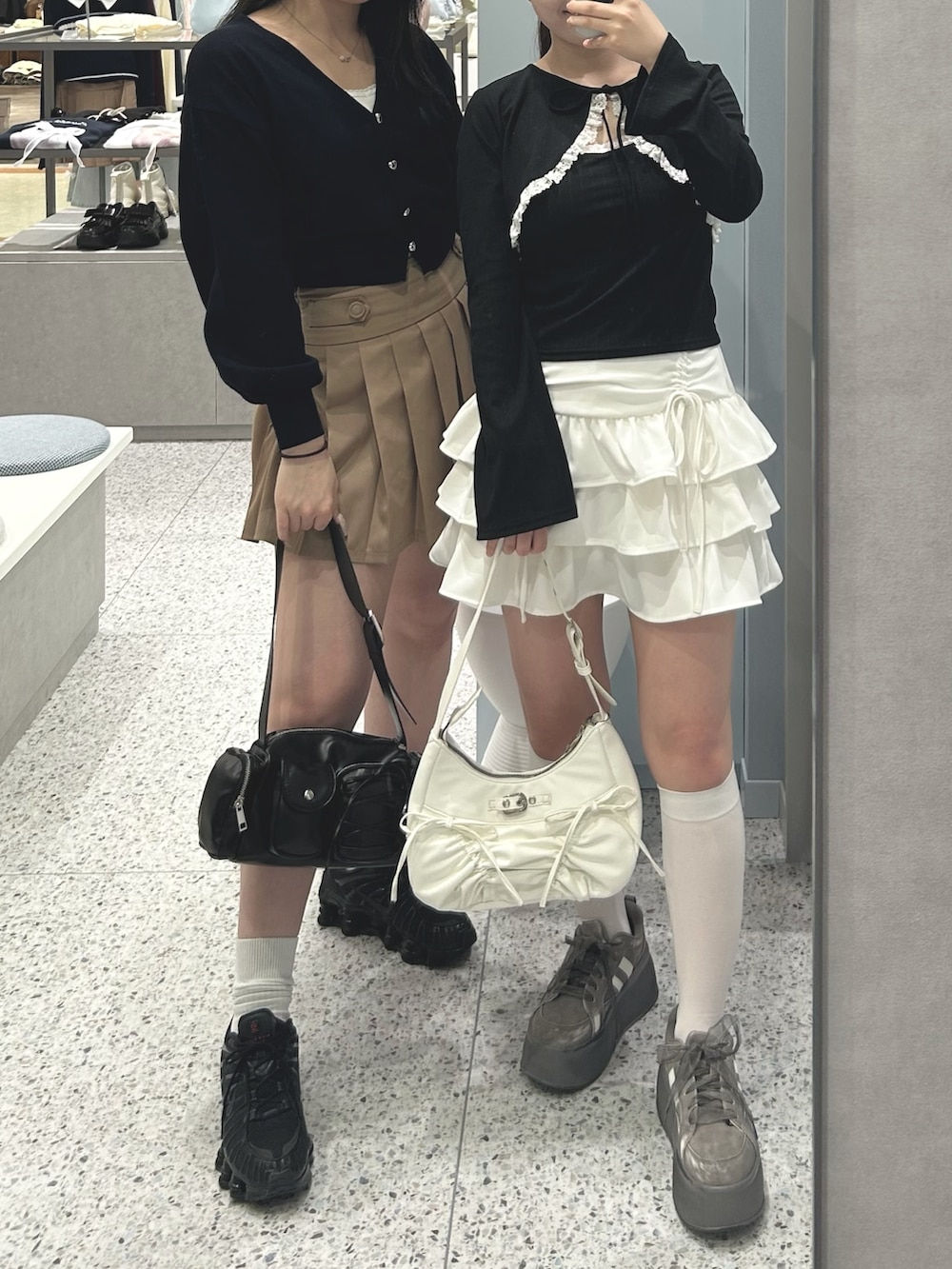 ブラック系のアンサンブル、ホワイト系のスカート、ホワイト系のショルダーバッグを着用したレディースの春コーディネートの3枚目の写真