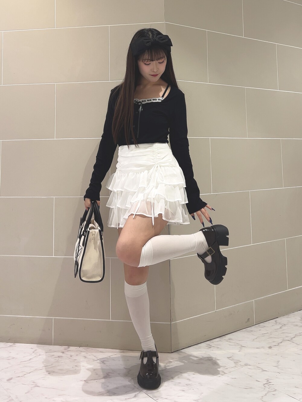 ブラック系のTシャツ/カットソー、ホワイト系のスカート、ホワイト系のトートバッグを着用したレディースの春コーディネートの2枚目の写真