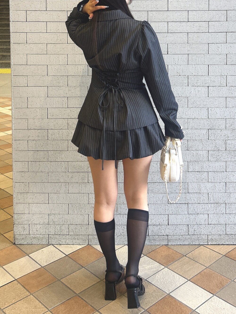 グレー系のテーラードジャケット、グレー系のスカート、ブラック系のキャミソールを着用したレディースの冬コーディネートの4枚目の写真