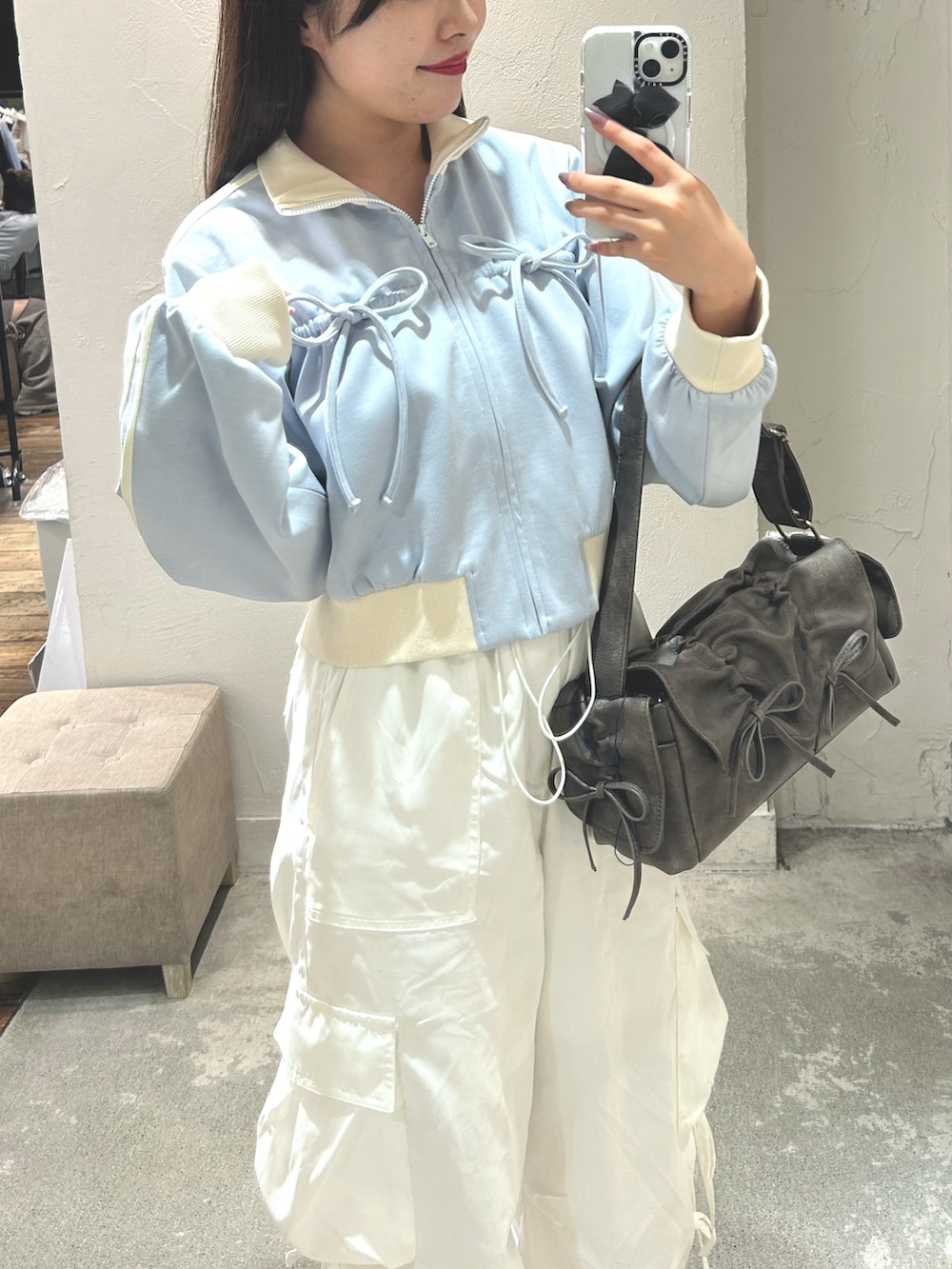 ブルー系のスウェット、ホワイト系のキャミソール、ブラック系のショルダーバッグを着用したレディースの夏コーディネートの4枚目の写真