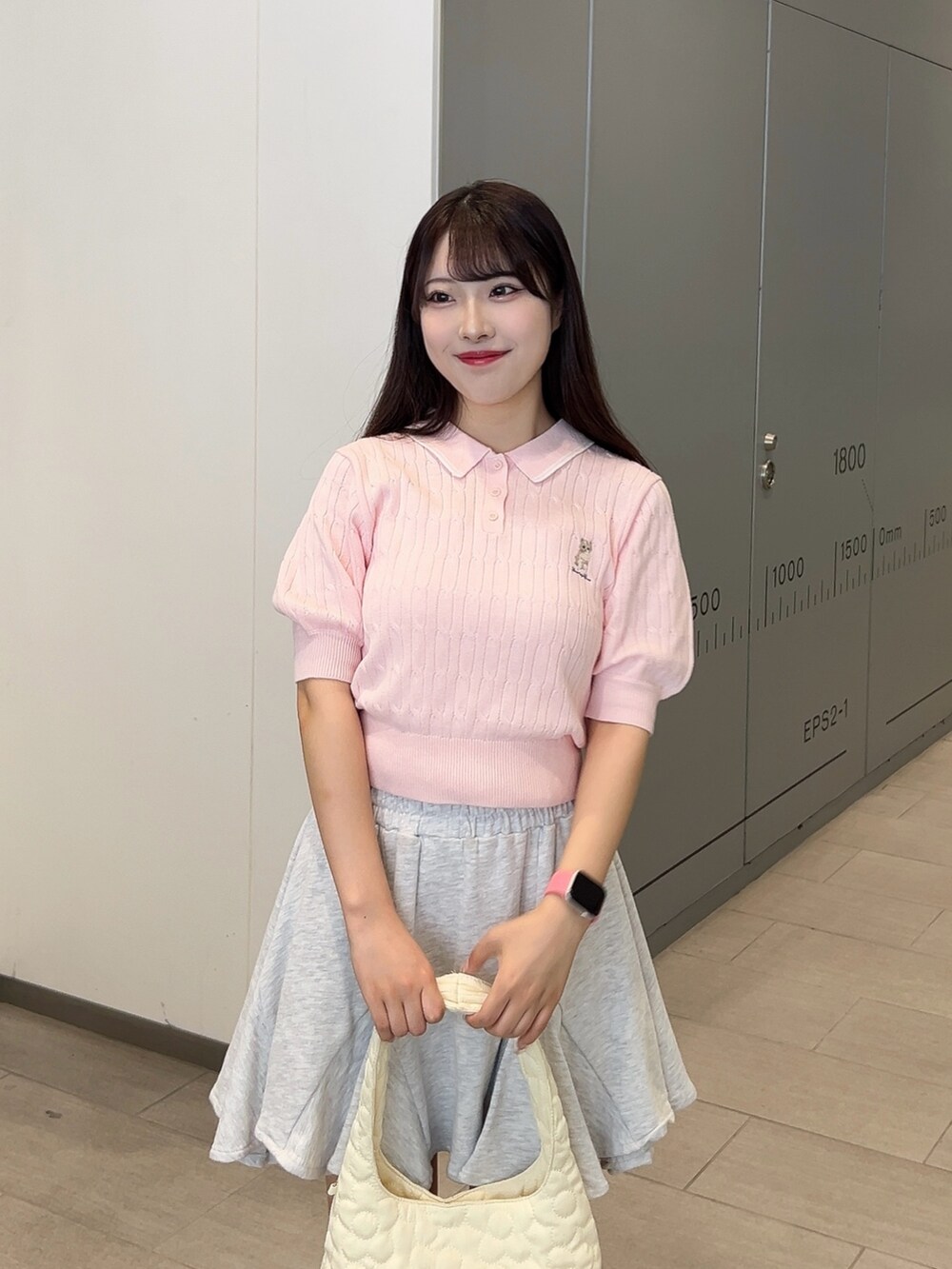 ピンク系のニット/セーター、ベージュ系のスカート、ホワイト系のショルダーバッグを着用したレディースの夏コーディネートの3枚目の写真