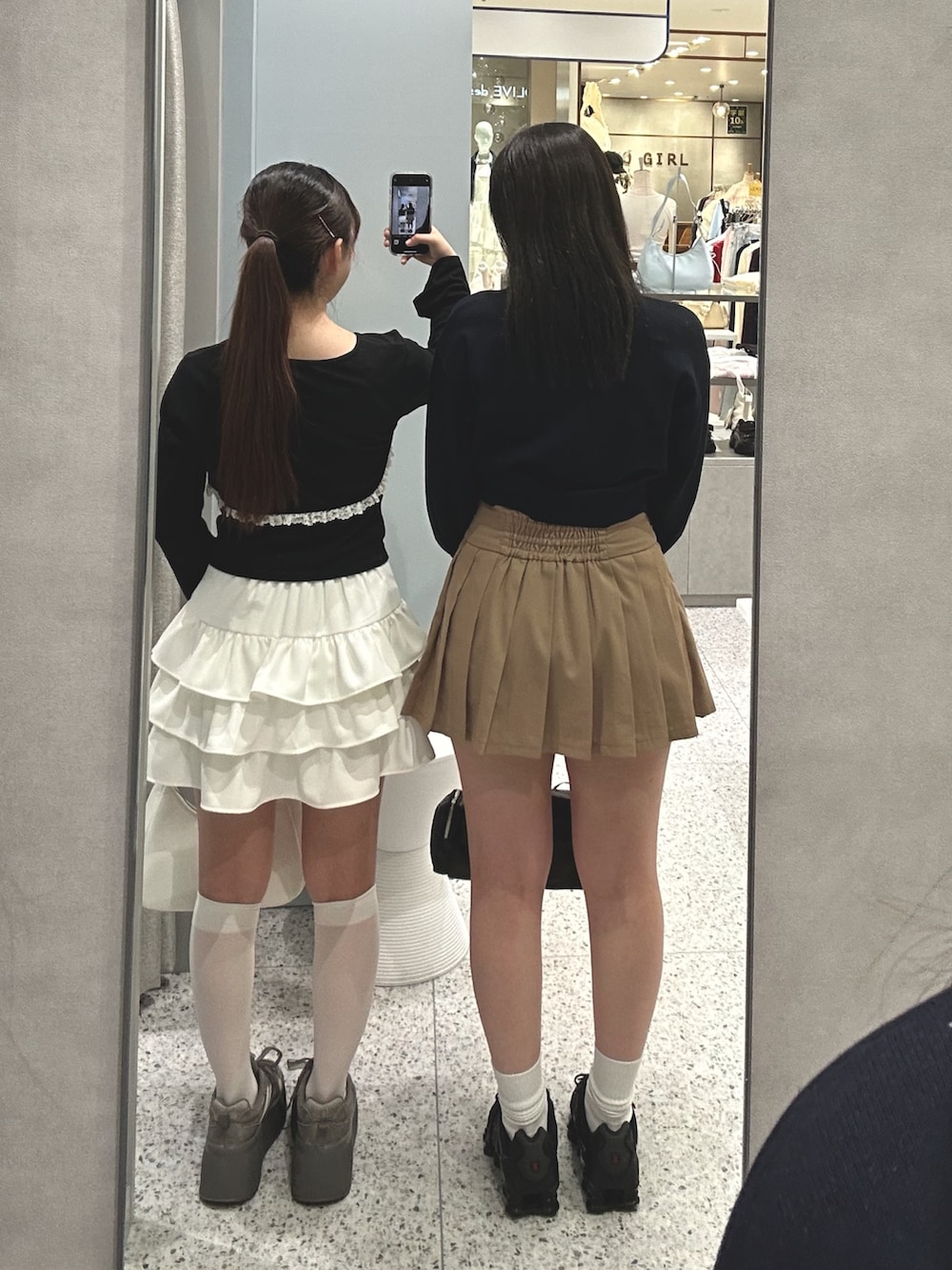 ブラック系のアンサンブル、ホワイト系のスカート、ホワイト系のショルダーバッグを着用したレディースの春コーディネートの2枚目の写真