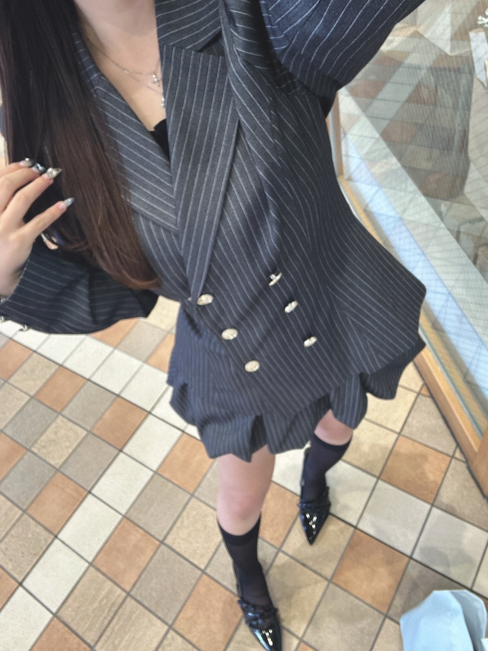 グレー系のテーラードジャケット、グレー系のスカート、ブラック系のキャミソールを着用したレディースの冬コーディネートの5枚目の写真