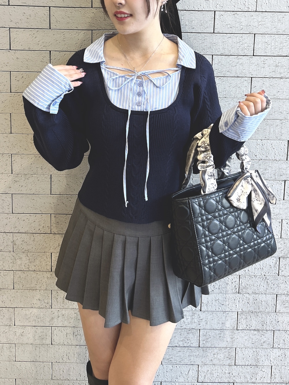 ブルー系のニット/セーター、グレー系のスカート、ブラック系のトートバッグを着用したレディースの冬コーディネートの4枚目の写真