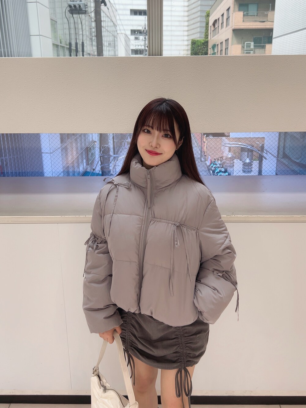 グレー系のダウンジャケット/コート、ホワイト系のTシャツ/カットソー、グレー系のスカートを着用したレディースの夏コーディネートの4枚目の写真