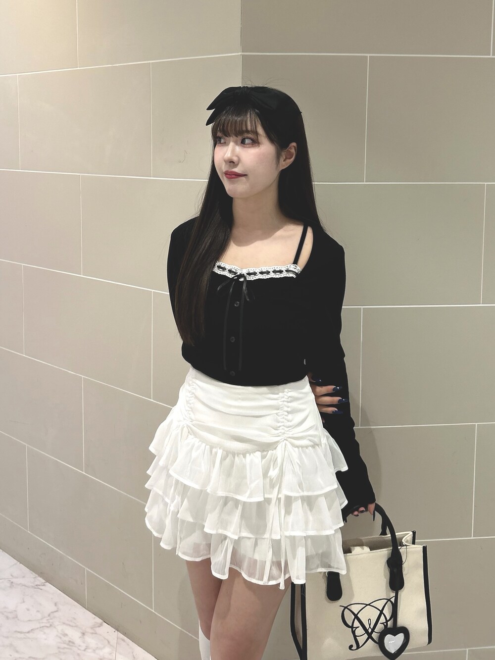 ブラック系のTシャツ/カットソー、ホワイト系のスカート、ホワイト系のトートバッグを着用したレディースの春コーディネートの3枚目の写真