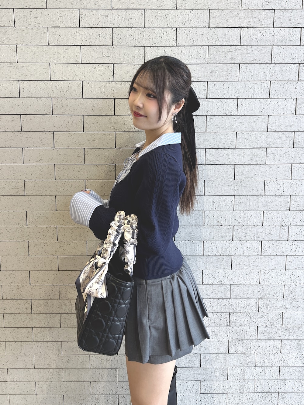 ブルー系のニット/セーター、グレー系のスカート、ブラック系のトートバッグを着用したレディースの冬コーディネートの3枚目の写真