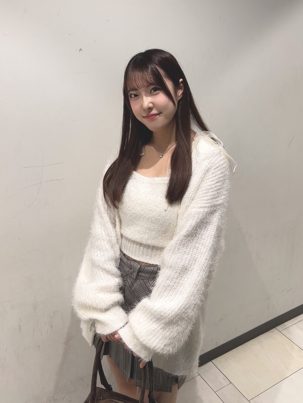 ホワイト系のアンサンブル、ホワイト系のカーディガン/ボレロ、ブラウン系のスカートを着用したレディースの秋コーディネートの6枚目の写真