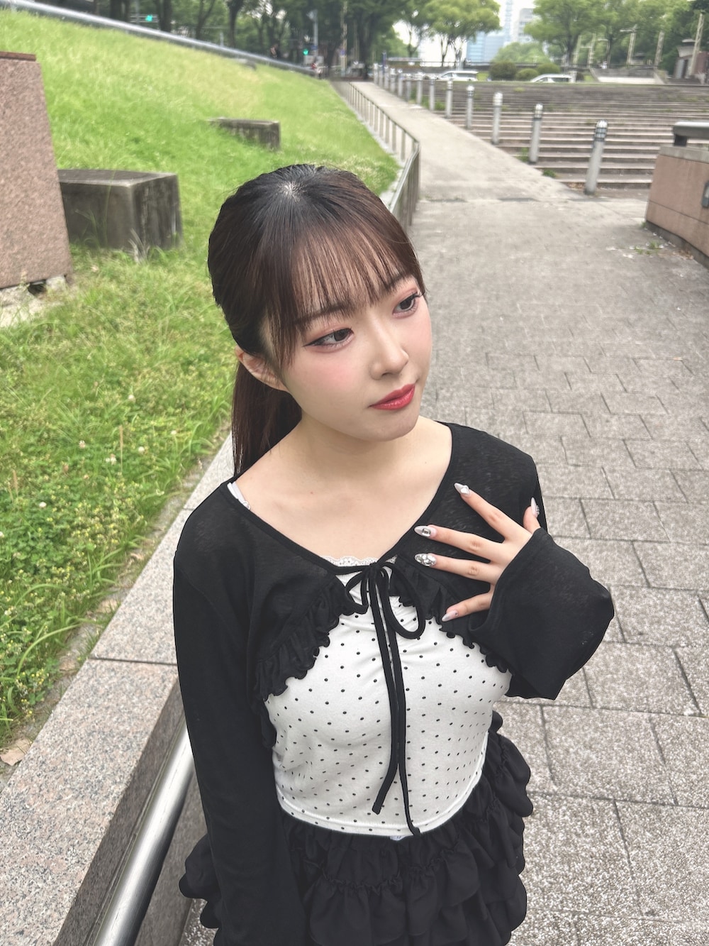 ブラック系のカーディガン/ボレロ、ブラック系のスカート、ホワイト系のサンダルを着用したレディースの夏コーディネートの3枚目の写真