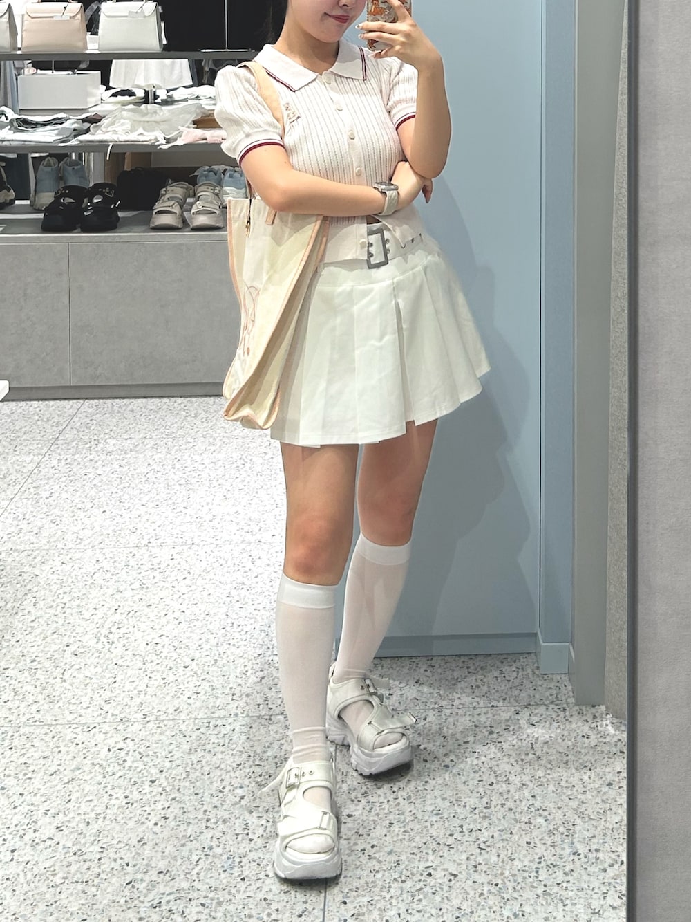 ピンク系のポロシャツ、ホワイト系のスカート、ホワイト系のサンダルを着用したレディースの夏コーディネートの3枚目の写真