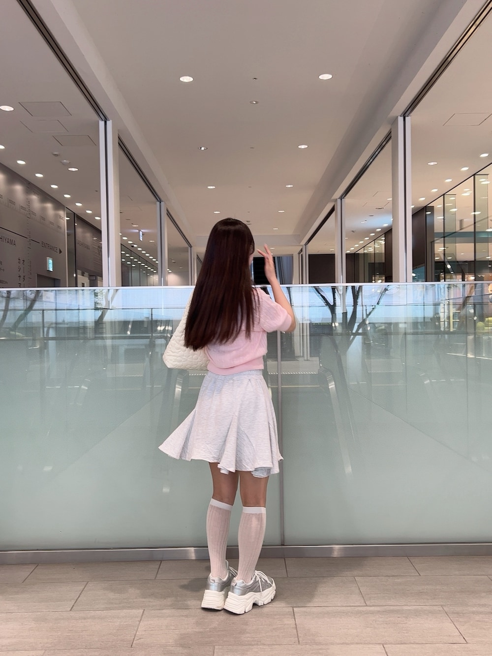 ピンク系のニット/セーター、ベージュ系のスカート、ホワイト系のショルダーバッグを着用したレディースの夏コーディネートの2枚目の写真