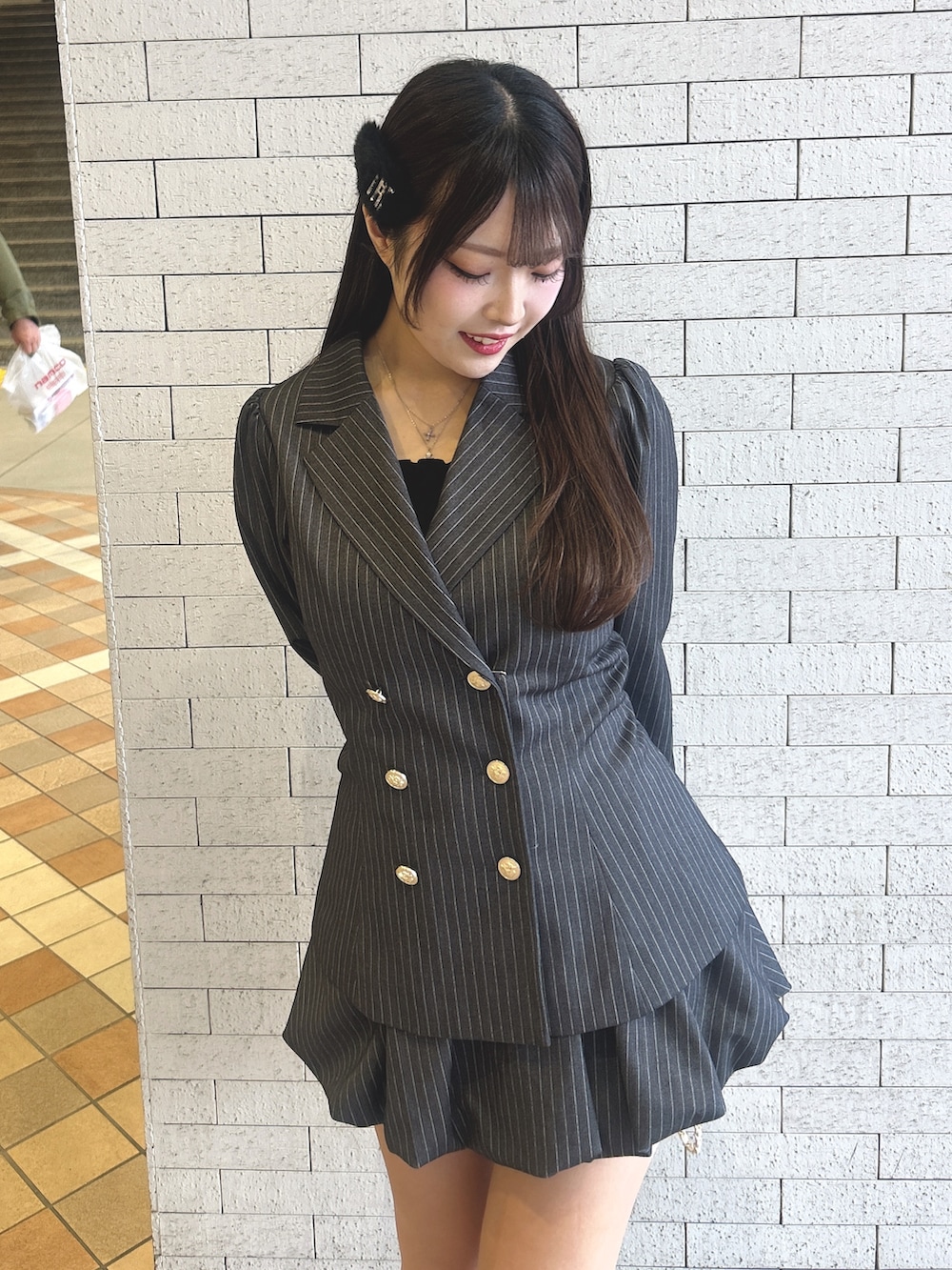 グレー系のテーラードジャケット、グレー系のスカート、ブラック系のキャミソールを着用したレディースの冬コーディネートの2枚目の写真