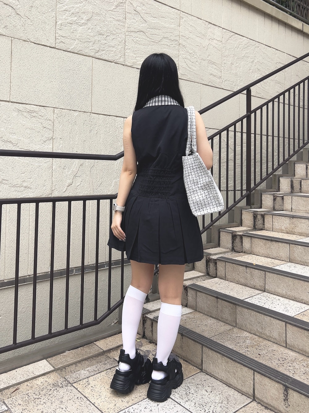 ブラック系のワンピース、ホワイト系のトートバッグ、ブラック系のサンダルを着用したレディースの夏コーディネートの2枚目の写真