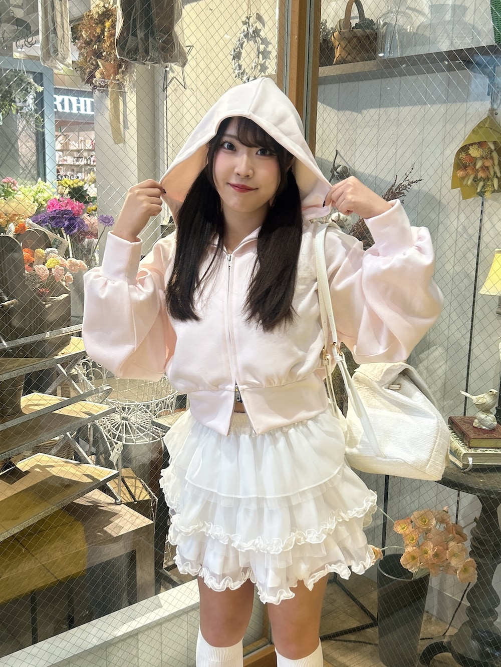 ピンク系のパーカー、ホワイト系のスカート、ホワイト系のバックパック/リュックを着用したレディースの春コーディネートの3枚目の写真