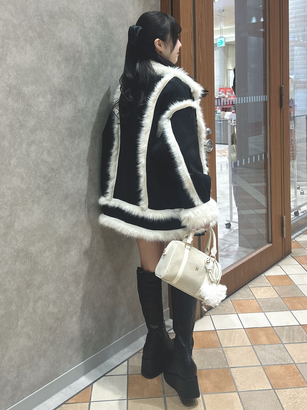 ブラック系のムートンコート、ブラック系のニット/セーター、ブラック系のスカートを着用したレディースの冬コーディネートの3枚目の写真