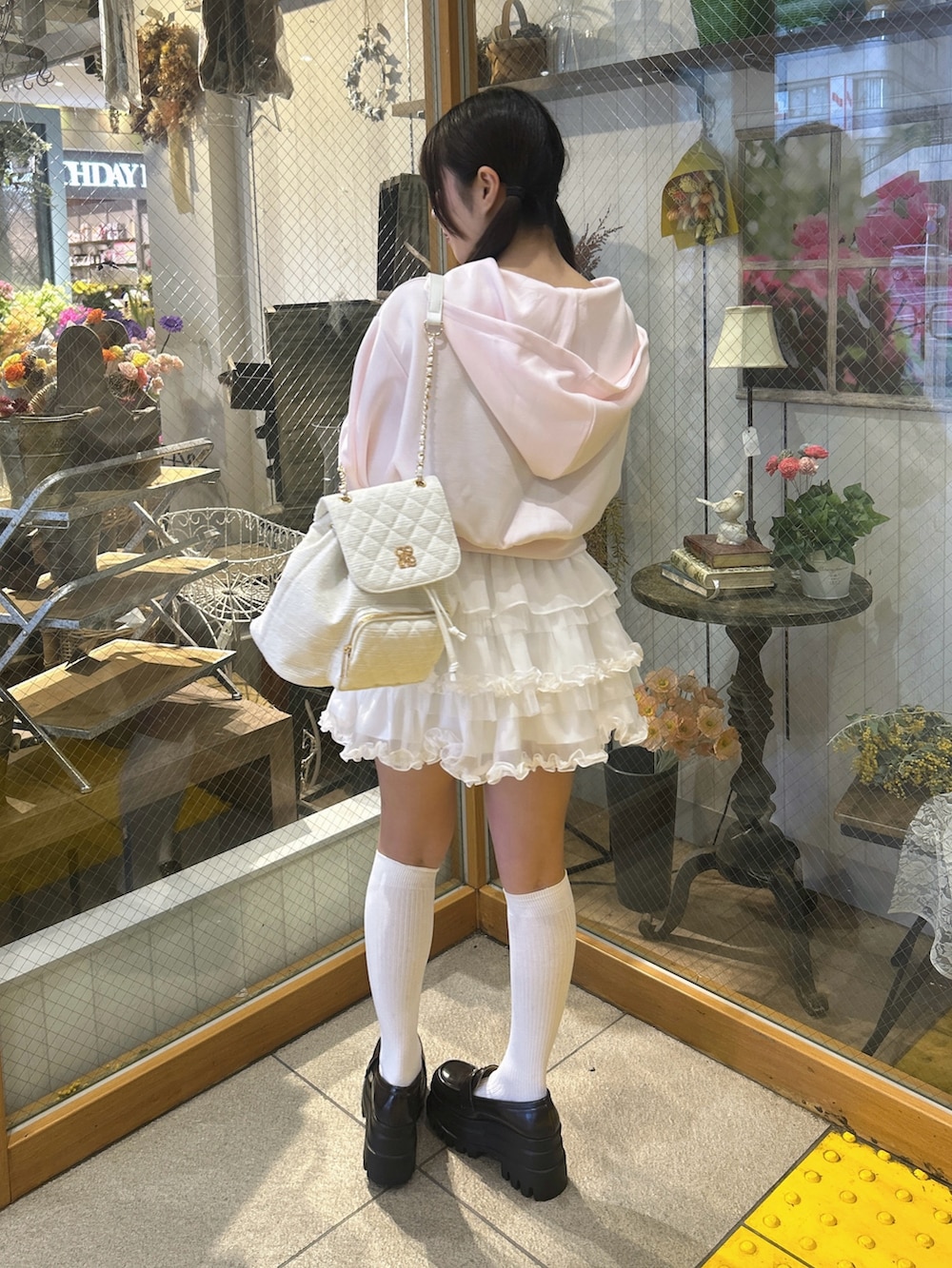 ピンク系のパーカー、ホワイト系のスカート、ホワイト系のバックパック/リュックを着用したレディースの春コーディネートの2枚目の写真