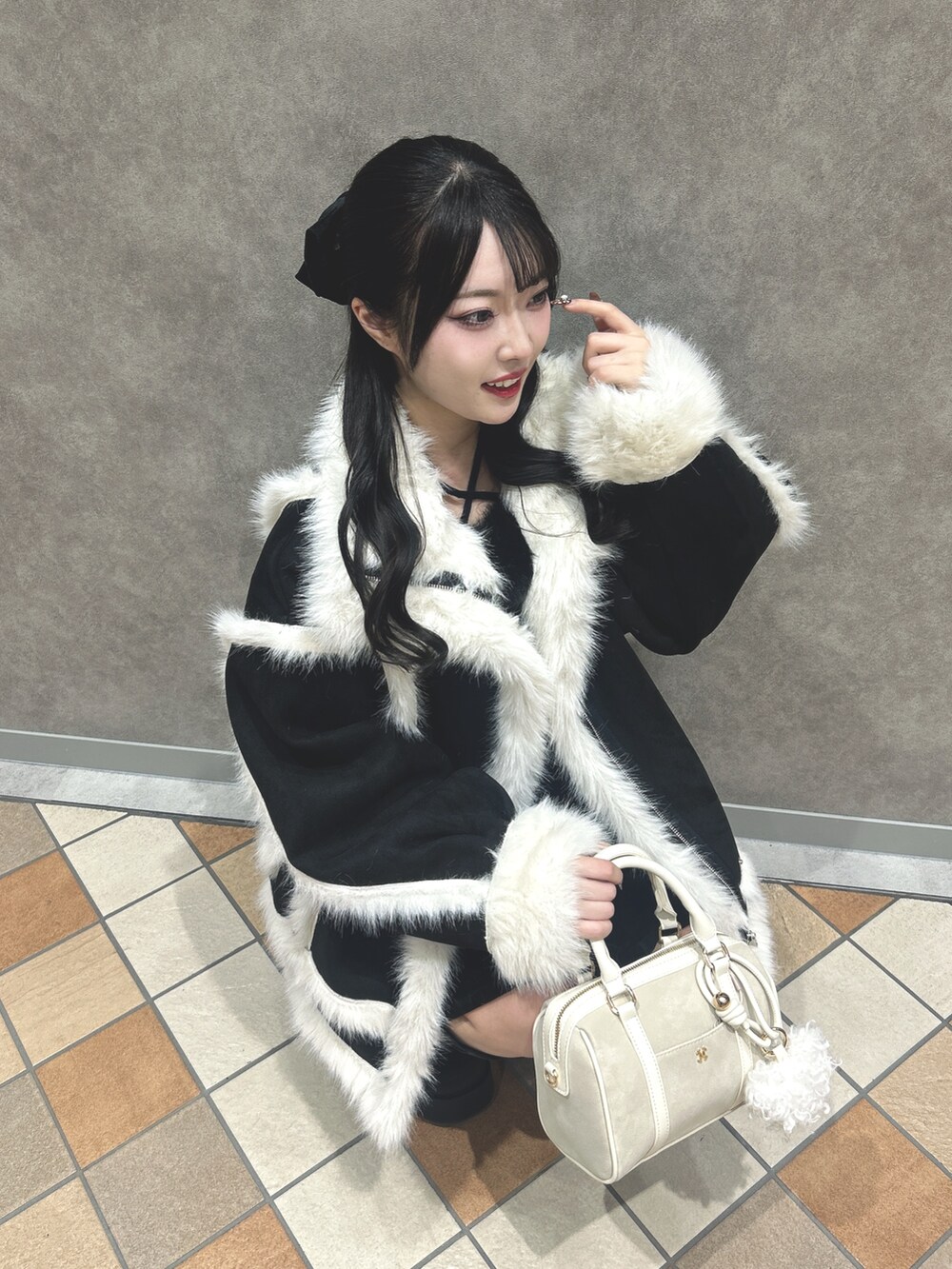 ブラック系のムートンコート、ブラック系のニット/セーター、ブラック系のスカートを着用したレディースの冬コーディネートの5枚目の写真