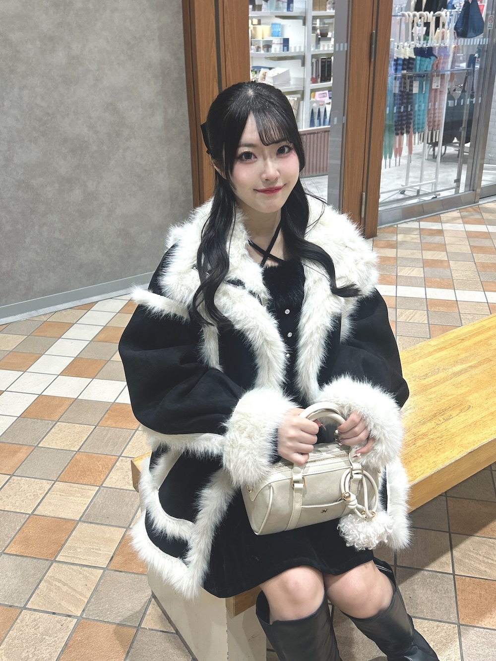 ブラック系のムートンコート、ブラック系のニット/セーター、ブラック系のスカートを着用したレディースの冬コーディネートの4枚目の写真