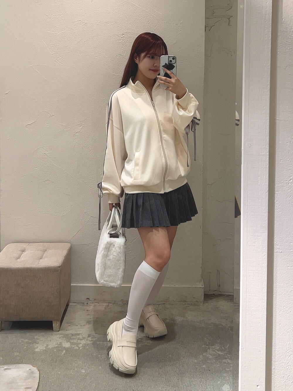 ホワイト系のジャージ、ホワイト系のトートバッグ、ホワイト系のローファーを着用したレディースの秋コーディネートの4枚目の写真