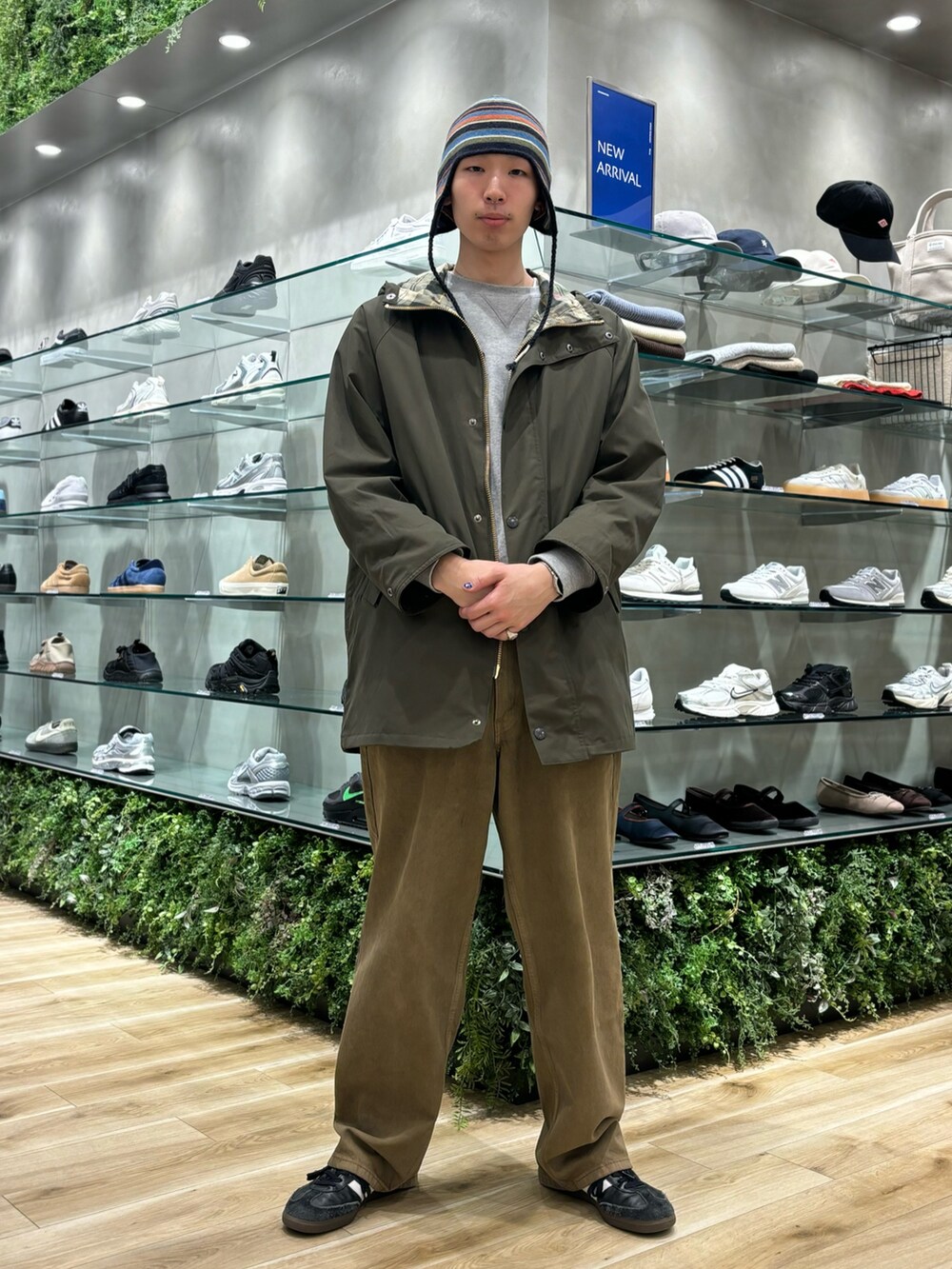 グリーン系のモッズコート、ブラウン系のデニムパンツ、ブラック系のスニーカーを着用したメンズの秋コーディネートの3枚目の写真