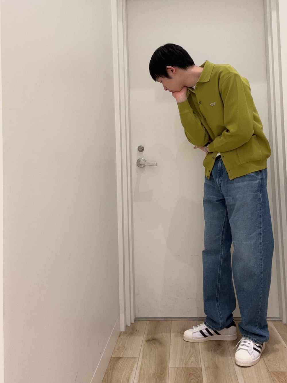 イエロー系のカーディガン/ボレロ、ブルー系のデニムパンツ、ホワイト系のスニーカーを着用したメンズの冬コーディネートの3枚目の写真